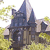 Pixelated image of a dark blue castle with multiple towers and a pointed spire, set against a light background with yellowish foliage on the sides.