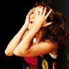 Woman with long brown hair covering face with both hands, mouth open in distress, wearing red and black top with yellow accents against dark background.