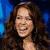 A woman with long brown hair appears in three distinct poses: smiling, singing into a microphone, and holding an object near her chest.
