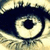 A pixelated close-up of a large eye with a dark blue iris and black pupil, set against a light beige background with subtle darker accents.