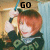 A person with short red hair holds a blue-handled object above their head in the top , while the bottom shows the same person in a yellow shirt with hands raised, both displaying 'GO' and 'LEVIN!' text