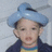 A child wearing a light blue turban and dark jacket over a yellow shirt with blue trim, shown in three with subtle facial expression changes