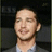 Pixelated image of a person in a dark suit with a light shirt, next to black pixelated text on a white background.