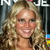 A pixelated close-up of a person with long, wavy blonde hair smiling, set against a dark background with partial white text and colorful elements.