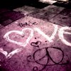 A static icon with a pinkish-purple background featuring white neon-style text spelling 'LOVE' and a small black heart symbol below the text.