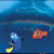 Pixelated static image of two cartoon fish in blue water background with one orange and white fish on the right, a smaller light blue fish on the left, and yellow underwater vegetation at bottom left.