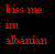 Red pixelated text on black background reads 'kiss me in albanian' with distinct letter spacing and no additional visual elements.