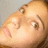 Pixelated close-up of a person's face showing eyes, nose, and mouth with light skin tone against a muted gray background.
