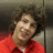 A person with curly brown hair wearing a red collared shirt appears in a of four , with one showing text overlay
