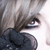 Pixelated close-up of a figure with light brown hair, dark eyes, and a black garment against a pale background.