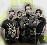 Five pixelated figures in dark clothing stand closely together against a light background with yellow-green gradient.