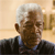 Pixelated image of a person with white hair wearing a dark jacket over a light blue shirt against a blurred background.