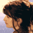 Pixelated static image of a person's profile with curly hair against a gradient background.