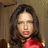 Pixelated image of a person with long dark hair wearing red clothing against a muted brown background.