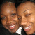 Two people in formal attire smile closely together, with one person's head positioned slightly left of center and the other right.