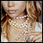 A woman with light brown hair wears multiple strands of white pearls around her neck, visible in a cropped close-up.