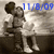 Two figures in grayscale tones stand close together, one holding a large dark circular object, with blue text reading '11/8/09' in the upper right.