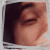 Pixelated close-up of a person's face showing closed eyes, dark hair, and light skin tone against a dark background.