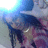 A pixelated image of a person with dark hair and a light-colored top, partially obscured by a bright light source in the upper left corner.