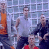 Group of people in dynamic poses against a background, wearing orange, gray, black, and red clothing with varied expressions
