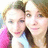 Two people in close proximity, one wearing pink and white clothing with brown hair, the other in light blue with dark hair against a blurred background.