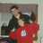 Two people embrace in a room with one wearing red shirt and white logo, while blue background displays stacked text 'me and shane = gangstah' in pixelated font.