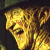 Pixelated golden-yellow animal face with dark brown and black accents, cropped closely on the head against a dark background.