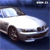 Pixelated image of a white car with dark wheels and a blue background, viewed from a low angle.