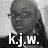 Pixelated grayscale portrait of a person with long hair and glasses, overlaid with bold white text reading "Kj.W." on the lower portion.