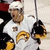 Pixelated image of a hockey player in white uniform with yellow accents, wearing helmet and holding stick.