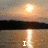 Sunset over water with a dark landmass, displaying sequential text: 'I', 'LOVE', 'JENNA' in white pixelated font.