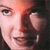 Pixelated close-up of a person's face showing eyes, nose, mouth, and partial hair against a dark background with warm lighting.