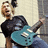 A pixelated image of a person holding a teal electric guitar, with red and gray background sections containing text.
