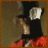 A pixelated figure in black and red clothing with a white collar, viewed from the side against a brown background.