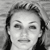 Black-and-white pixelated static image of a person's face with visible hair and facial features, rendered in grayscale tones on a gray background.