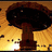 A mushroom-shaped icon with a dark brown cap and stem against a golden background, featuring subtle pixelated light effects.