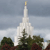 A pixelated static image shows a tall white spire with a golden tip against a cloudy sky, surrounded by dark green trees at the base.