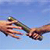 Pixelated static image of two hands reaching toward each other against a blue background, with no visible text or distinct branding elements.
