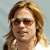 Pixelated portrait of a person with light brown hair wearing dark sunglasses and a white top against a light blue background.