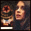 A pixelated image of a person with long dark hair and a striped garment, featuring a circular red-and-brown symbol on the left side.
