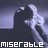Pixelated image of a dark figure with light hair against a gradient background, featuring the word 'miserable' in white block letters at the bottom.