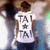 Pixelated static image of a person wearing a white shirt with repeated 'TAL' text and a star symbol, standing against a blurred background.