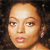Pixelated close-up of a person's face with light brown skin tone, brown eyes, and pink lips against a dark background.