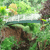 Pixelated green and brown landscape with a white and blue horizontal shape resembling a boat or bridge over water, surrounded by foliage.