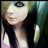 Pixelated static image of a person with long dark hair, light skin tone, and closed eyes wearing a black top against a blurred greenish background.