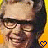 A pixelated image of a person with dark hair and glasses, wearing a light-colored cap, against a yellow background with blue heart symbols.