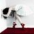 A pixelated static image shows a large white and black robot-like figure with a long arm extending toward two small red humanoid figures on a dark red platform against a light gray background.