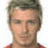 Pixelated portrait of a person with short brown hair, light skin, and a neutral expression wearing a red and dark-colored shirt against a white background.