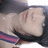 Pixelated close-up of a person lying down with eyes closed, wearing dark clothing and a pink-and-blue striped item, against a dark background.