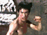 A shirtless man with dark hair performs martial arts movements against a stone wall background, captured in showing varied poses and expressions